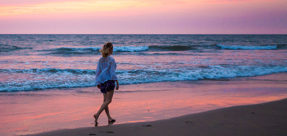 Girl walking on the beach at sunset