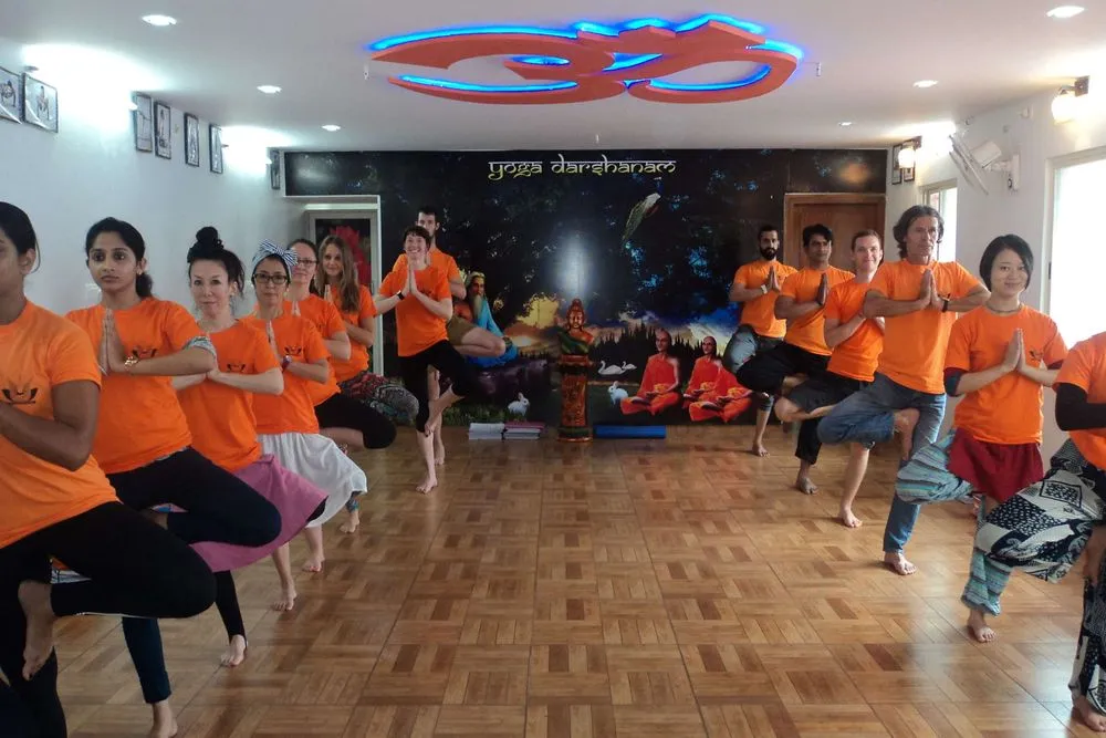 Students doing tree pose in yoga teacher training school in India