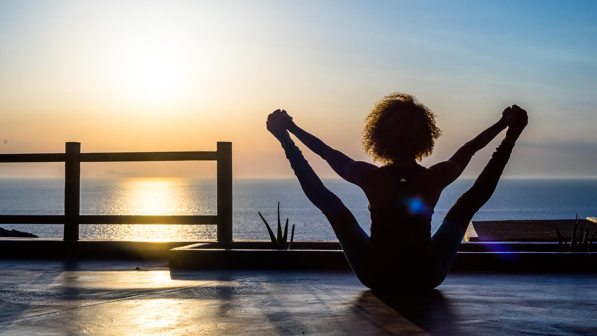 Joanna of Alpha Yoga School practicing yoga as the sun sets in Greece