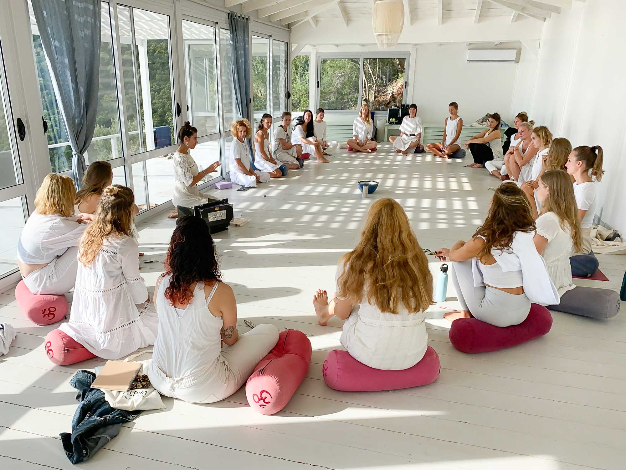 Opening ceremony as yoga students sit in a circle at yoga teacher training in Europe, Greece