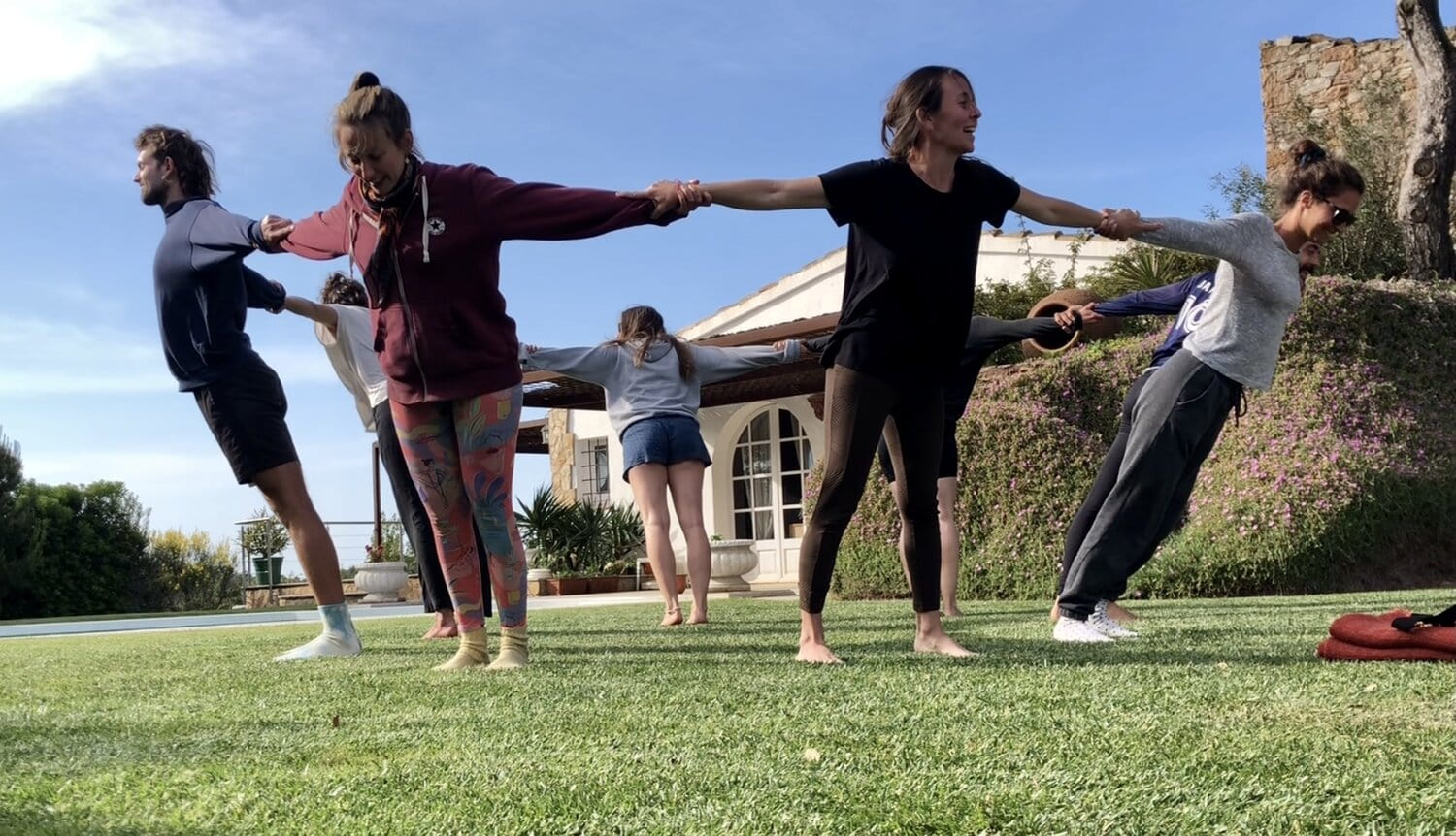 class of yoga students holding hands in a team-building exercise with Nydum yoga school in Europe