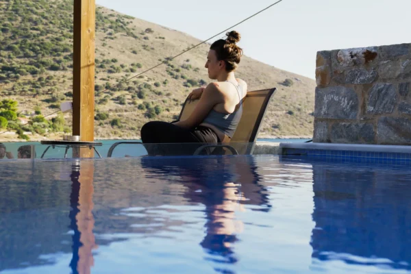 P1000462 (1) yoga student sitting in a chair by the pool, looking at the ocean after yoga class in Evia, Greece
